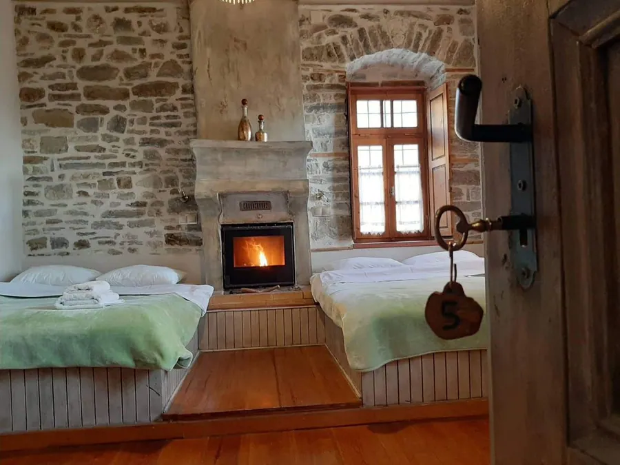 Δωμάτιο με πέτρινο τζάκι και δύο κρεβάτια